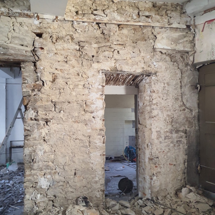 Chantier : mur en pierre mis à nu autour d'une baie